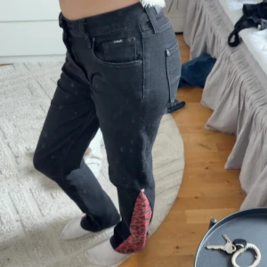 Svarta jeans med leoparddetalj från Pepe Jeans - Snygga svarta jeans från Lee Jeans med en cool leoparddetalj vid bensluten. De har en tight passform och är högmidjade, vilket ger en smickrande siluett. Perfekta för att ge din outfit en extra edge.