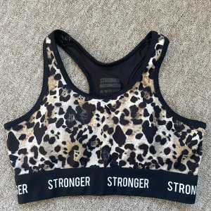 Leopardmönstrad sporttopp från Stronger - Säljer en snygg leopardmönstrad sporttopp från Stronger. Den har en elastisk kant med logotypen 'STRONGER' och är perfekt för träning. Fint skick!!!😍😍❣️❣️