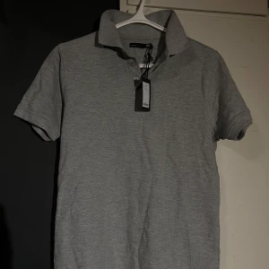 Grå pikétröja från Lager - Oanvänd piké från lager säljer då den inte passade mig. 