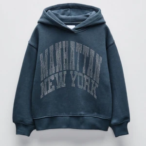 Mörkblå hoodie med glitter - Snygg mörkblå hoodie med texten 'Manhattan New York' i glittriga bokstäver på framsidan. Perfekt för en avslappnad stil med en mysig huva och ribbade muddar vid ärmslut och nederkant.
