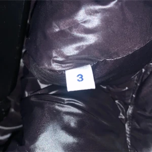 Svart dunväst från Moncler - Snygg svart dunväst från Moncler med dragkedja och emblem på bröstet. Perfekt för lager-på-lager under kyliga dagar. Västen har en glansig finish och praktiska fickor med dragkedja.