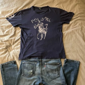 Mörkblå t-shirt från Polo Ralph Lauren - Vintage Mörkblå t-shirt från Polo Ralph Lauren.  T-shirten är tillverkad i 100% bomull och har en klassisk passform med korta ärmar. Ny pris är runt 700kr. Är i storlek S/M då den passar båda bra. Jag är runt 180cm och 62kg. Tröjan är använd som det märks i kragen. Priset går att diskutera i rimliga mängder.