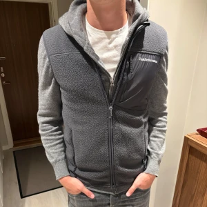Grå fleece väst från Peak Performance - Säljer en grå fleece väst från Peak Performance. Jackan har en bröstficka med dragkedja och långa ärmar. Perfekt för nu för våren och sommar.Väldigt bra skick. 