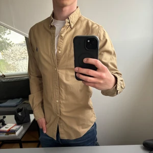 Beige skjorta från Ralph Lauren - Säljer en stilren beige skjorta från Ralph Lauren. Perfekt för en avslappnad men ändå uppklädd stil. Storlek small och i mycket fint skick!