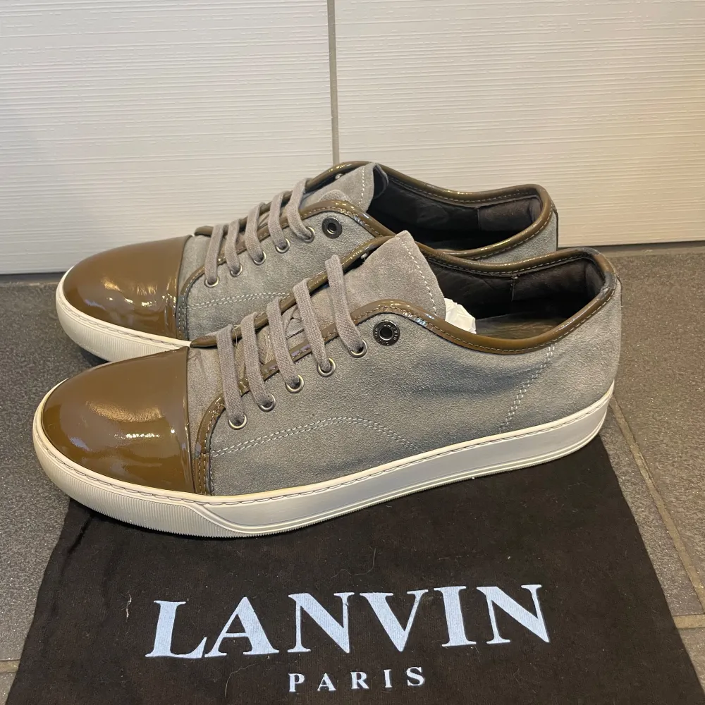 Snygga grå sneakers från Lanvin med glansig brun tåhätta och snörning. Skorna har en stilren design med en kombination av mocka och skinn. Storlek 43 passar också 44. Skorna är i topp skick nästan som nya. Priset är förhandlingsbart vid en snabb affär:). Kengät.