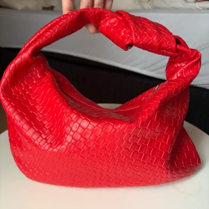 Röd axelväska med flätat mönster - ALDRIG ANVÄND! En röd handväska med ett unikt flätat mönster och ett handtag som är knutet. Väskan har en guld dragkedja och ett rött foder inuti❤️‍🔥