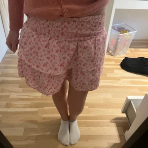 Rosa blommig kjol från Gina Tricot - Supersöt rosa kjol från Gina Tricot med små blommor och volanger. Kjolen har bred smock i midjan och dubbla lager tyg som ger en fin volym. Perfekt för vår och sommar!