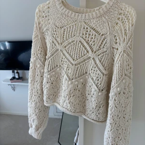 Beige stickad tröja med spetsmönster - Säljer en beige stickad tröja då den inte längre kommer till någon användning. Perfekt nu till sommaren att ha över en klänning, men passar också väldigt bra till ett par jeans eller till en snygg kjol. 