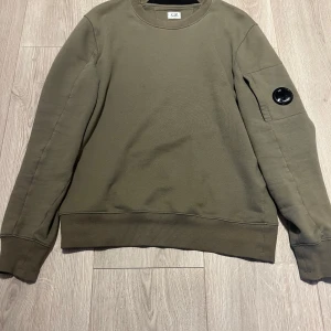 Olivgrön sweatshirt från C.P. Company - Säljer nu en mörk/ olivgrön sweatshirt från C.P. Company. Perfekt för en stilren och avslappnad look. Inköpt på Carrie of Carl för inte så länge sedan. Har tyvärr tappat bort kvittot. Skriv om ni har några frågor.