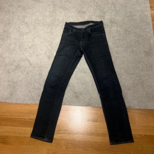 Mörkblå jeans från Tiger of Sweden - Säljer ett par mörkblå jeans från Tiger of Sweden med klassisk femficksdesign och raka ben. Jeansen har normal passform och är tillverkade i ett slitstarkt denimtyg. Storlek m