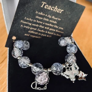 Fin och originell gåva till en uppskattad lärare inför skolavslutningen! - Handgjort elastiskt armband med lila glaspärlor och fjärilsberlock. Medföljer gör också en fin text på engelska och allt kommer i en vacker presentask. Beständig och speciell gåva till en uppskattad lärare. Perfekt till terminsavslutningar och studenter. Nytt!