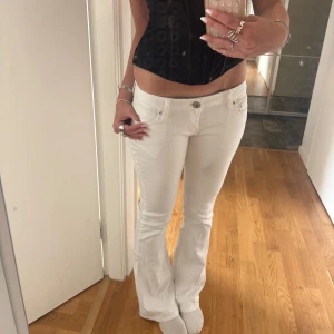 Vita bootcut jeans med låg midja - vita bootcut jeans med snygga nitar på bakfickan och låg midja. Bra skick men en fläck (kolla tredje bilden). Står ingen storlek, men skulle säga S, jag är 177