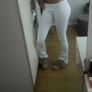 Vita ribbade byxor med utsvängda ben - Nypris 699kr.   OANVÄNDA, endast testade. Säljer ett par vita ribbade byxor med utsvängda ben och låg midja. Byxorna har en tight passform upptill och är tillverkade i ett stretchigt material som sitter snyggt på kroppen. Perfekta för en trendig och avslappnad look. 