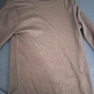 Brun ribbad långärmad tröja - Säljer en brun ribbad långärmad tröja med rund halsringning. Perfekt basplagg att ha i garderoben och lätt att matcha med olika outfits.