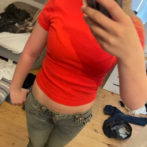 Röd ribbad topp från Vero Moda - Säljer en röd ribbad topp från Vero Moda. Toppen har korta ärmar, rund halsringning och en tight passform. Perfekt att styla med jeans eller kjol för en snygg vardagslook.andvänd två gånger