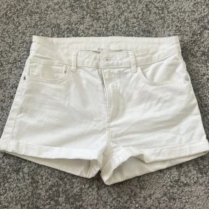 Vita jeansshorts med låg midja från H&M - Snygga vita jeansshorts med låg midja och klassisk femficksdesign. Shortsen har bälteshällor och uppvikta benslut, perfekta för mu på sommar.❤️