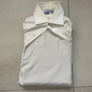 Vit skjorta från Tommy Hilfiger - Klassisk vit skjorta från Tommy Hilfiger med lång ärm och knappar framtill. Skjortan har en stilren design med bröstficka och klassisk krage. Perfekt till dig som gillar en clean och tidlös look.