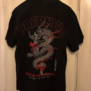 Svart t-shirt med tryck  - Svart t-shirt med stort rött motiv på ryggen. Strl S (oversized)