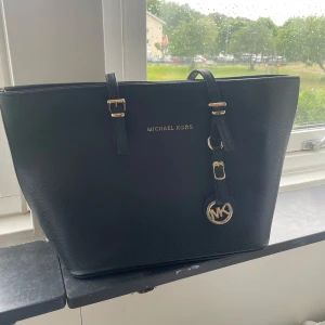 Svart handväska från Michael Kors - Snygg svart handväska från Michael Kors. Fick den va min syster som inte använder den längre och har inte helelr kommit till användning för mig! Lite av färgen på loggan har gått bort men verkligen inget man märker (se sista bilden) skriv gärna för frågor eller fler bilder! Pris går att diskutera 🥰