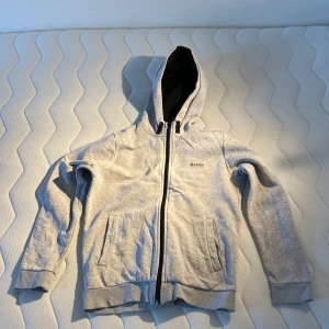Grå Hugo Boss zip hoodie  - Äkta och i väldigt bra skick. Köpt på Boozt för 1085 kr. Hör av vid intresse och priset kan diskuteras!