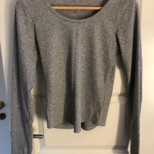 Grå ribbad långärmad topp - Säljer en enkel grå, ribbad, långärmad tröja med rund halsringning. Perfekt basplagg som passar till det mesta och är superbekväm att ha på sig. Är i storlek s 🩶