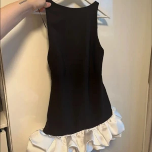 Svart miniklänning med vit volangkant - Snygg svart miniklänning med bred vit volang längst ner från Zara. Prislapp är kvar och inuti är inbygga shorts💕säljer då den va för liten, kan också mötas upp i Stockholm 
