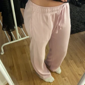 Ljusrosa mjukisbyxor från Pull&Bear - Säljer ett par ljusrosa mjukisbyxor från Pull&Bear med dragsko i midjan och raka ben. Byxorna har en avslappnad passform och är tillverkade i mjukt bomullsmaterial. Lite smutsiga längst ner, men inget man tänker på. 