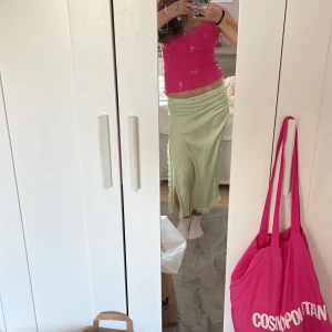 Ljusgrön satinkjol med spetsdetaljer - Säljer en ljusgrön långkjol i satin med fina spetsdetaljer längs nederkanten och slitsen. Kjolen har en elegant och flowy passform som ger en snygg siluett.💚