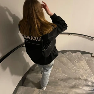 Jacka - Svart vindjacka från Weekday med tryck på ryggen. Texten är aningen missfärgad och är mer åt det beiga hållet som på bild 2. En skavank visas på sista bilden.