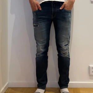 Replay Anbass jeans med slitningar - Säljer ett par blå Replay Anbass jeans med snygga slitningar och lätt tvättad look. Jeansen har normal passform och klassisk femficksdesign.  Storleken är 30/30, och dom är i riktigt bra skick. 