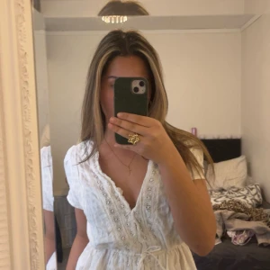 Vit spetsklänning med knyt i midjan från Gina Tricot - Supersöt vit klänning med spetsdetaljer och v-ringning från Indiska . Klänningen har korta ärmar, knyt i midjan och fina broderade detaljer längs kanten. Perfekt för sommarens alla tillfällen!