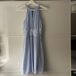 Ljusblå klänning med spetsdetalj i midjan - Säljer en ljusblå klänning med vackra spetsdetaljer i midjan. Perfekt för sommarens tillfällen. Från Vila. 