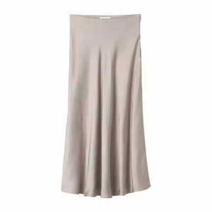 Beige satinkjol - Säljer en stilren beige långkjol i satin med mjukt fall och minimalistisk design. Perfekt för dig som gillar en clean och elegant look. Kjolen har en lätt glansig yta och sitter snyggt i midjan.