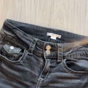 Svarta bootcut jeans  - Säljer ett par svarta bootcut jeans från Gina Tricot med låg midja och dubbla knappar framtill. Dem är sprättade längst ner och i storlek 158 men passar mig som är 165. Midjemått rakt över 35 cm innerbenslängden är 77-78 cm, ordinarie pris ca 360 kr