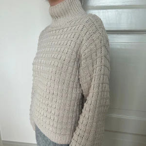 Beige stickad polotröja - Säljer en beige stickad polotröja. Tröjan har en hög polokrage och är lite boxig i modellen. Storlek xs men skulle säga att den är oversized.