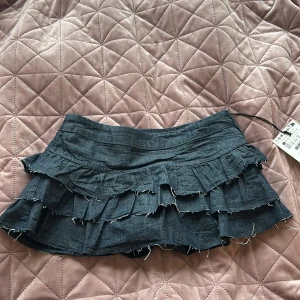 Mörkblå volang jeanskjol från Bershka - Supersöt mörkblå kort jeanskjol från Bershka med flera lager volanger och fransiga kanter. Den har en dragkedja på sidan och inbyggda shorts💙