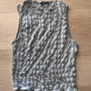 Blå ärmlös linnetopp från Gina Tricot - Säljer en blå ärmlös linnetopp från Gina Tricot med ett unikt rutigt strukturerat tyg. Perfekt för varma dagar och enkel att matcha med olika outfits.