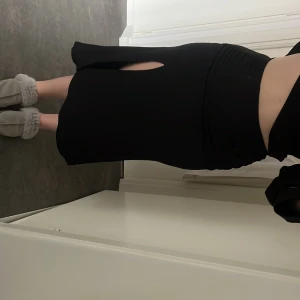 Svart långkjol med slits - Säljer en svart långkjol med hög midja och en snygg slits framtill. Kjolen har en åtsittande passform och är tillverkad i ett stretchigt material som sitter bekvämt. Perfekt att styla med en crop top eller blus.