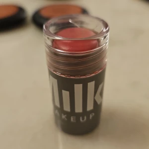 Milk Makeup Lip + Cheek Stick i färgen Rally - Milk Makeup Lip + Cheek Stick i nyansen Rally, en krämig multiprodukt för både läppar och kinder. Färgen är en kall rosa ton och sticket har en smidig, rundad form som gör appliceringen enkel. Perfekt för en naturlig och fräsch look. Endast testad och locket har tyvärr fått en liten spricka. 