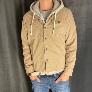 Beige overshirt från Jack & Jones - Säljer en beige overshirt från Jack & Jones med knappar framtill och två bröstfickor. Perfekt att bära som lager över en t-shirt eller hoodie. Den är något liten i storleken. Skick 8/10✅ Pris kan diskuteras vid snabb affär💸