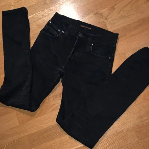 Svarta jeans från Nudie Jeans - Säljer ett par svarta jeans från Nudie Jeans med klassisk femficksdesign och raka ben. Jeansen model är Grim Tim. W29 L39. Pris kan diskuteras!