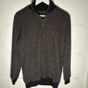 Ralph Lauren tröja - Mörkgrå tröja med halv dragkedja från Polo Ralph Lauren i storlek L. Klassisk modell med röd logga på bröstet, ribbade muddar och krage. Använd några få gånger och i mycket fint skick, passar både till vardag och lite mer uppklätt.  Hör av dig vid intresse! 🙌