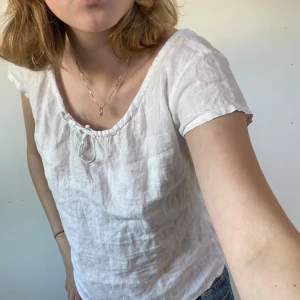 Vit linnetopp med knyt  - Säljer en vit linnetopp från InWear med korta ärmar och söt knytning vid halsringningen. Toppen har en avslappnad passform och är tillverkad i ett tunt, luftigt linnematerial – perfekt för varma dagar.