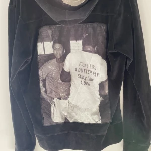 Limitato zip hoodie  - Svart hoodie från Limitato med dragkedja och två fickor framtill. På ryggen finns ett stort svartvitt tryck med texten 'Float like a butterfly, sting like a bee'. Perfekt för dig som gillar unika plagg med statement.