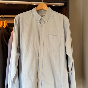 Ljusblå skjorta från J.Lindeberg - Säljer en stilren ljusblå skjorta från J.Lindeberg som är perfekt för sommaren. Slimfit! Ända minuset är att den blivit lite blekt i armhålan men det går kanske att få bort. I övrigt fin!