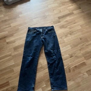 Mörkblå jeansbyxor från Evisu med broderad drake - Säljer ett par mörkblå jeans från Evisu med en stor, färgglad broderad drake på baksidan och klassisk Evisu-logga på fickan. Jeansen har raka ben och normal passform. Perfekta för dig som vill sticka ut med coola detaljer!