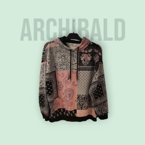 Patchwork hoodie i rosa och svart från Archibald - Säljer en hoodie med patchworkmönster i rosa och svart från Archibald. Tröjan har huva med dragsko och långa ärmar. Perfekt för dig som gillar unika mönster och streetwear-stil.