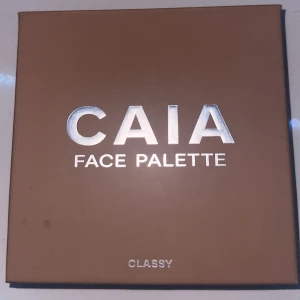 CAIA Face Palette Classy - Snygg face palette från CAIA i färgen Classy med fyra olika puder: contour, blush, bronzer och highlighter. Paletten har en spegel i locket och kommer i en stilren beige/brun förpackning. Perfekt för att skapa en fräsch och definierad look. Spegeln har kvar plastet på, och palletten är knappt använd då den inte passade mig! Köpt för 450 kr