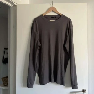 Grå långärmad tröja från Lager 157 - Säljer en enkel och stilren grå långärmad tröja från 157. Tröjan är ribbad och har en rund halsringning. Perfekt basplagg i garderoben och passar till många olika outfits.
