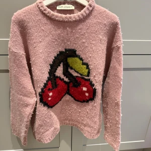 Rosa stickad tröja med körsbär från Our Legacy - Säljer en rosa stickad tröja från Our Legacy med ett stort körsbärsmotiv framtill. Använd fåtal gånger.